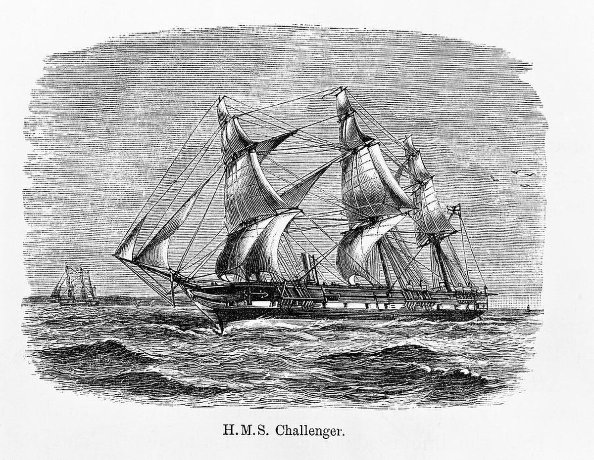 An engraving of HMS Challenger, a three-masted sailing ship with auxiliary steam power, on the open sea. The ship is shown with sails unfurled, and its name "H.M.S. Challenger" is printed below the image.