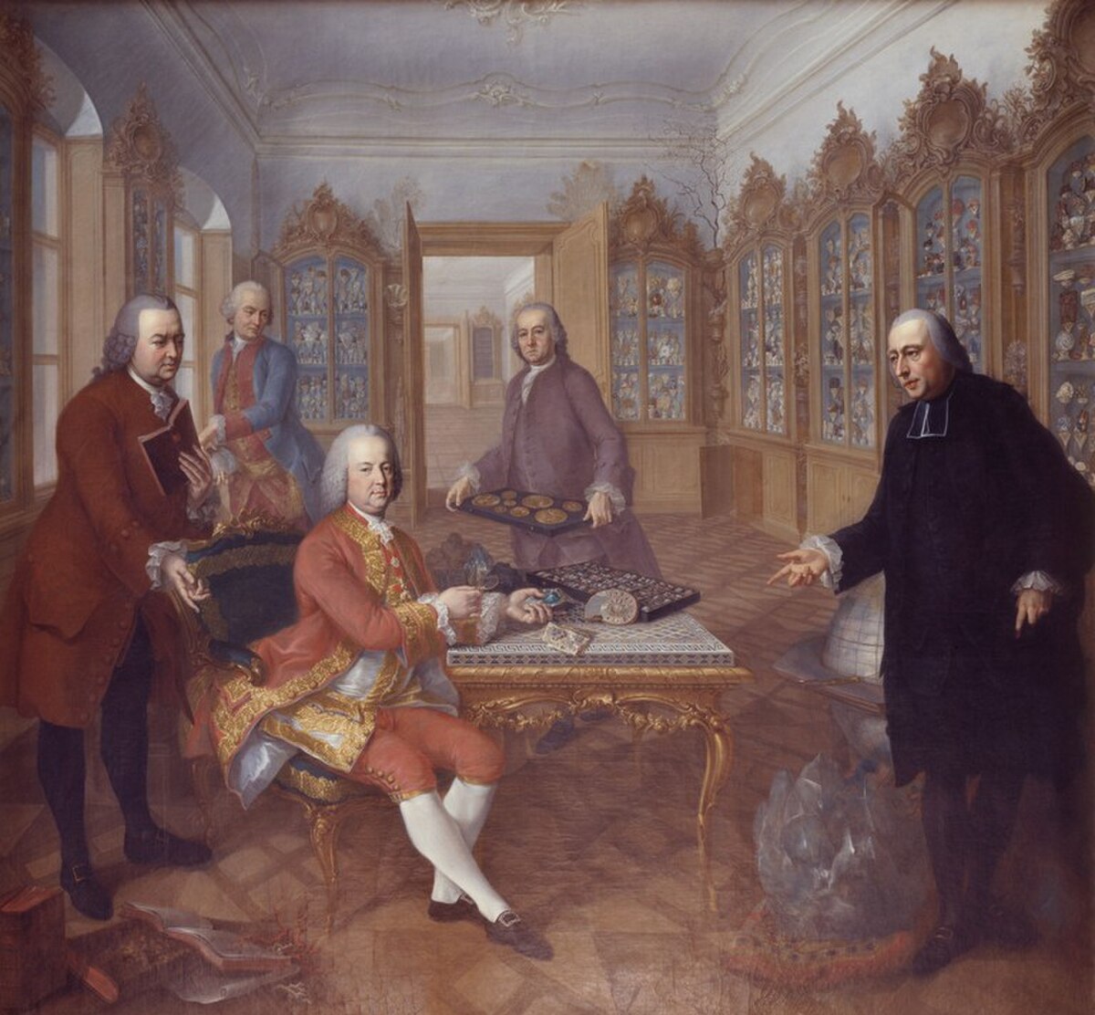 Painting depicting Francis I, Holy Roman Emperor, with his natural science advisors in a room filled with display cabinets. From left to right, the advisors are Gerard van Swieten, Johann Ritter von Baillou, Valentin Jamerai Duval (numismatist) and Abbé Johann Marcy, with Francis I seated at a table examining coins.