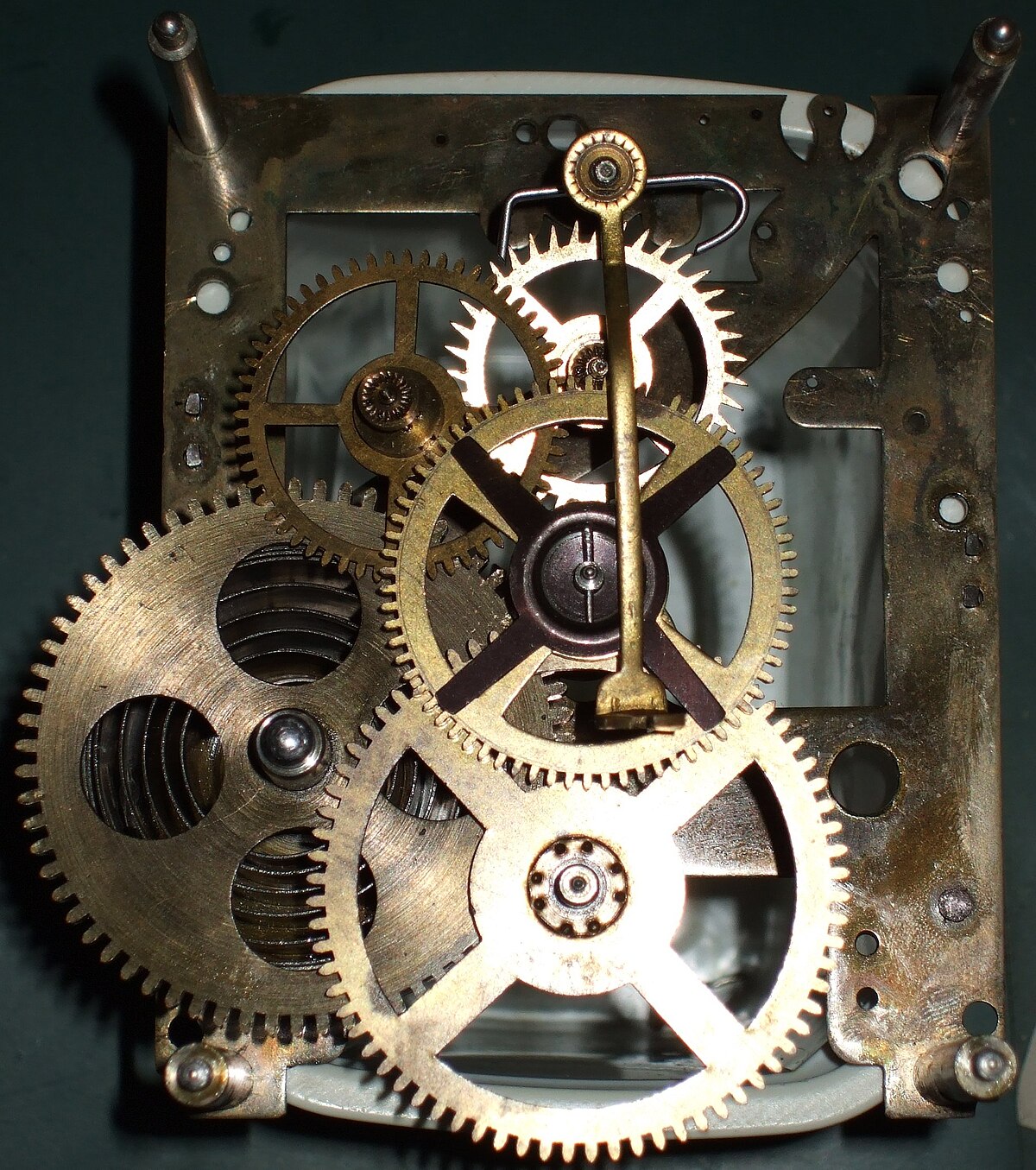 A close-up view of the intricate brass gears and mechanisms of a clockwork movement. Various gears of different sizes are visible, connected by axles and levers, demonstrating mechanical determinism.