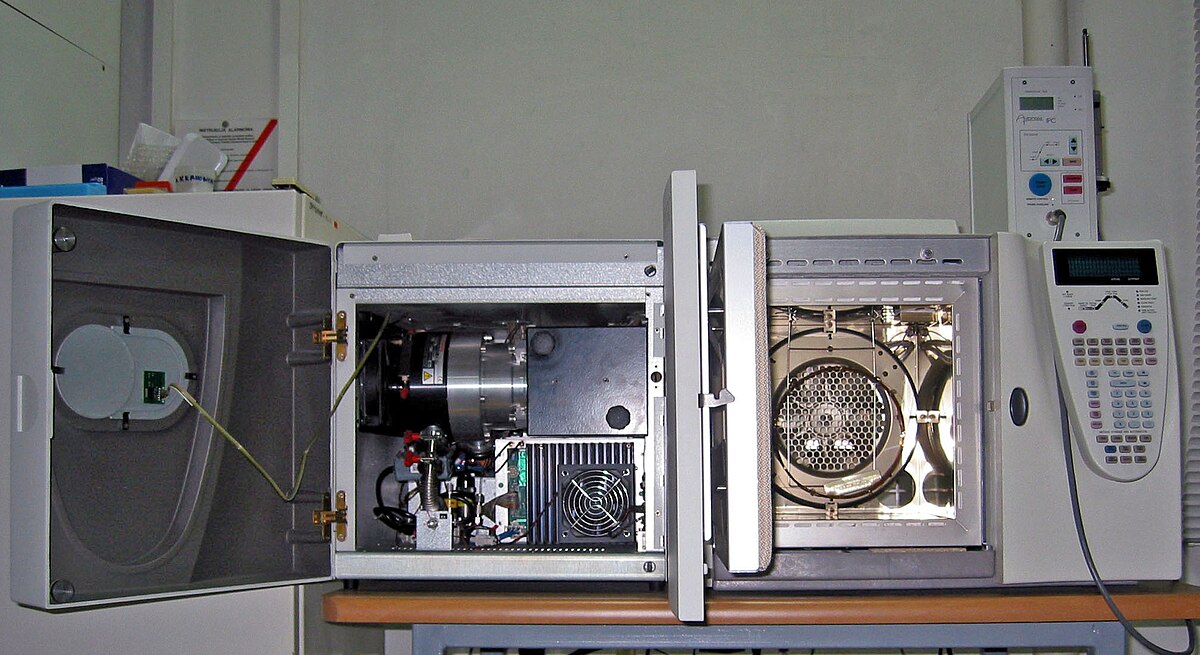 A GC-MS (Gas Chromatography-Mass Spectrometry) unit with its doors open, revealing the internal components. The gas chromatograph is on the right, and the mass spectrometer is on the left.