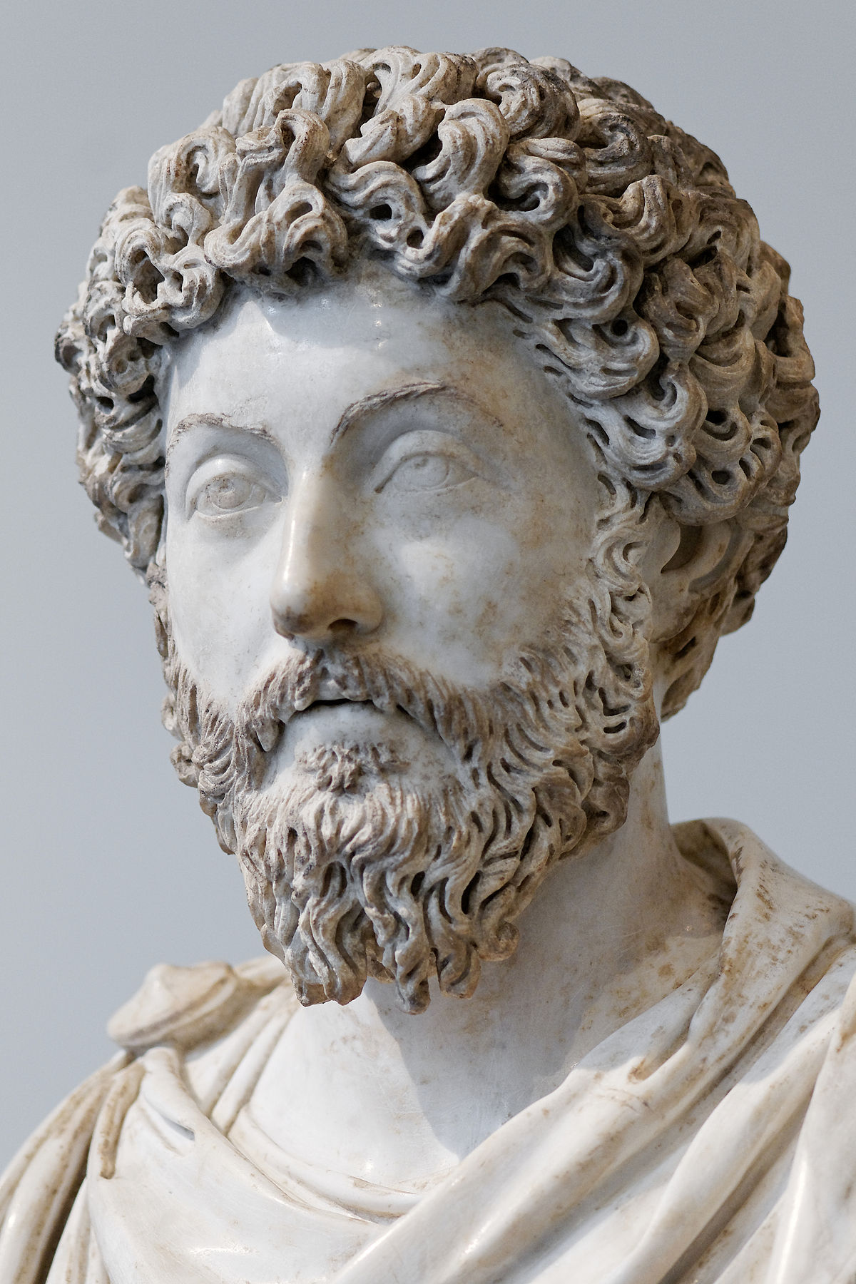 Marble bust of the Roman emperor and Stoic philosopher Marcus Aurelius, depicting him with curly hair and a full beard. The sculpture is highly detailed, capturing his mature features.