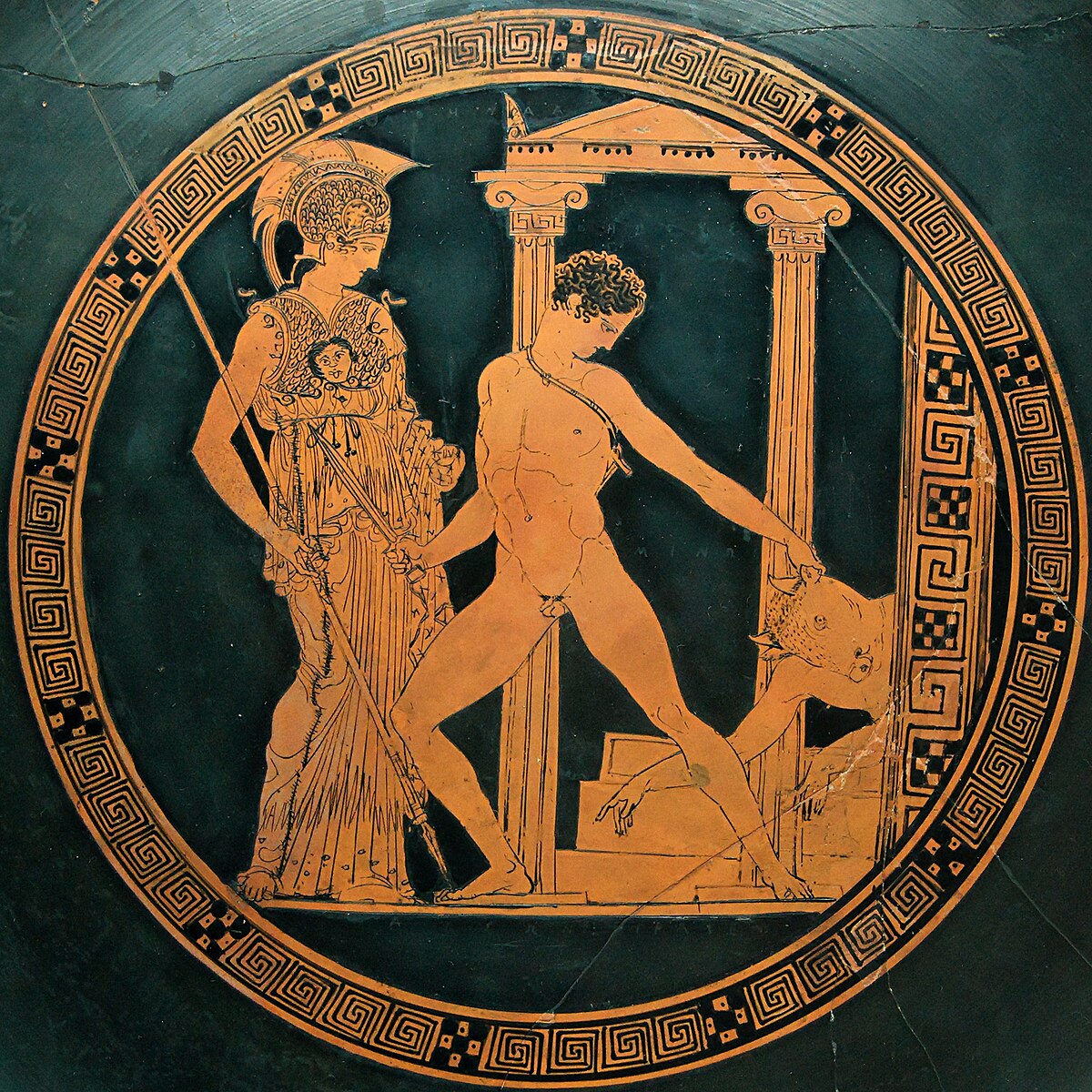The interior of a Greek kylix depicts Theseus slaying the Minotaur, with the goddess Athena standing to his left. The scene is rendered in red-figure style within a circular frame, surrounded by a meander pattern.