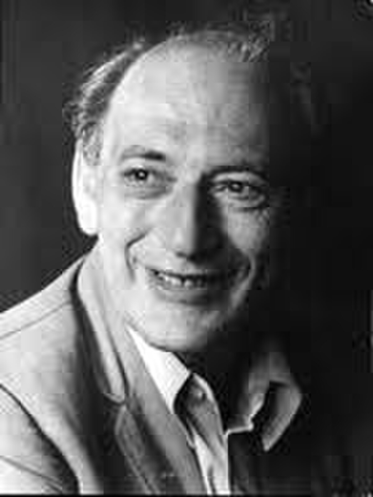 Black and white portrait of social psychologist Henri Tajfel, smiling and looking slightly to the right.