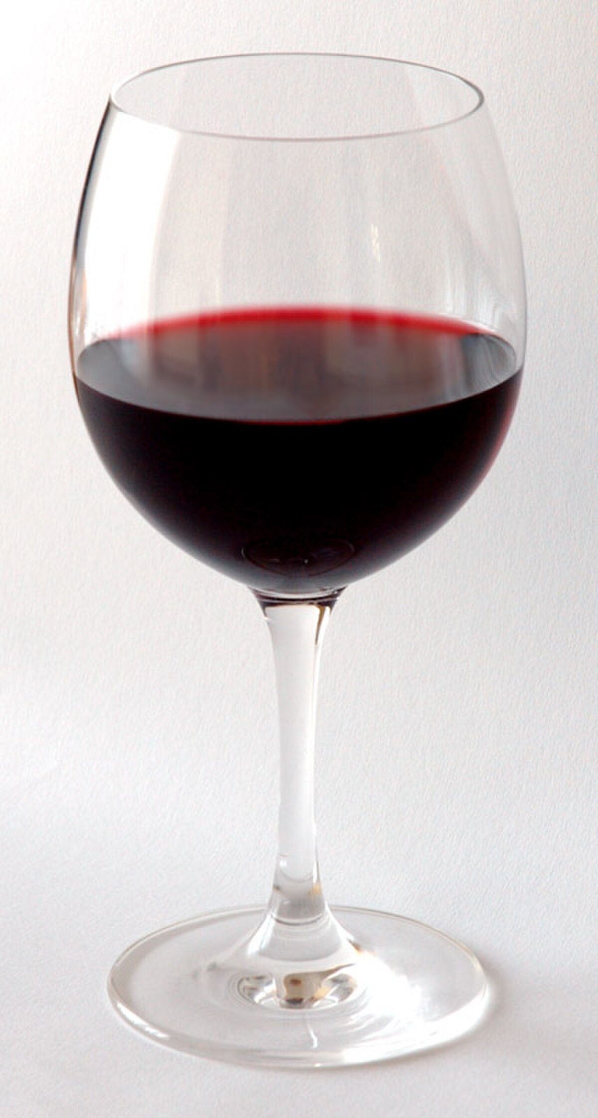 A clear wine glass is filled with red wine, showcasing the liquid's deep color and the glass's elegant stem and bowl. The source caption indicates a large (250 ml) glass of 12% ABV red wine has about three UK units of alcohol, and a medium (175 ml) glass has about two UK units.