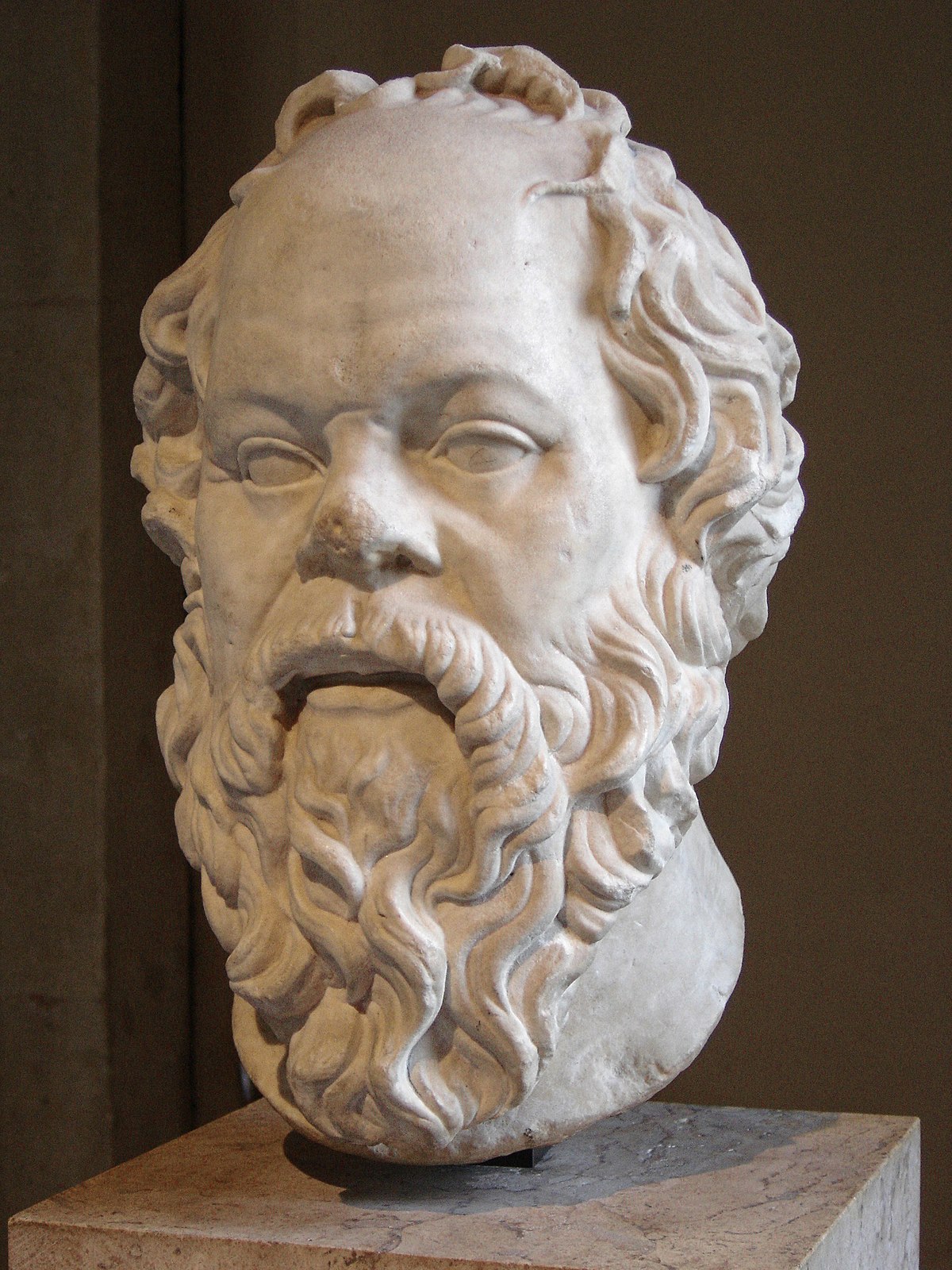 Marble bust of Socrates, a classical Greek philosopher, displayed at the Louvre. The sculpture depicts him with a distinctive bald head, a broad nose, and a full, curly beard.
