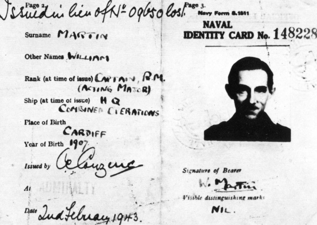 A black and white image of the naval identity card for "Major Martin," issued in lieu of a lost one, with a photograph of Captain Ronnie Reed. The card lists his surname as MARTIN, other names WILLIAM, rank as CAPTAIN, R.M. (ACTING MAJOR), ship as H.Q. COMBINED OPERATIONS, place of birth CARDIFF, year of birth 1907, and issued date as 2nd February 1943.