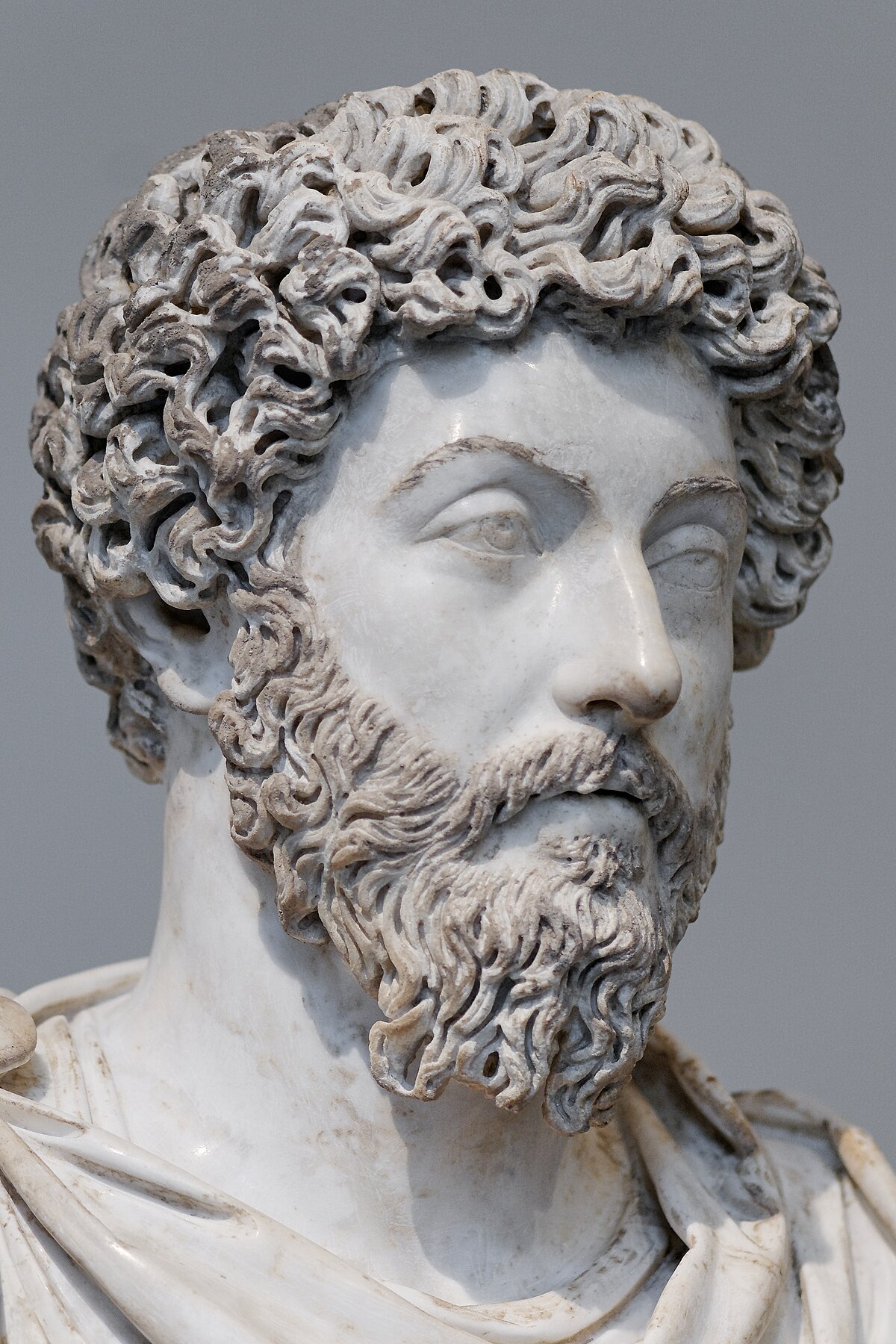 Marble bust of Marcus Aurelius, the Stoic Roman emperor, depicting him with curly hair and a beard. The sculpture captures a thoughtful expression.