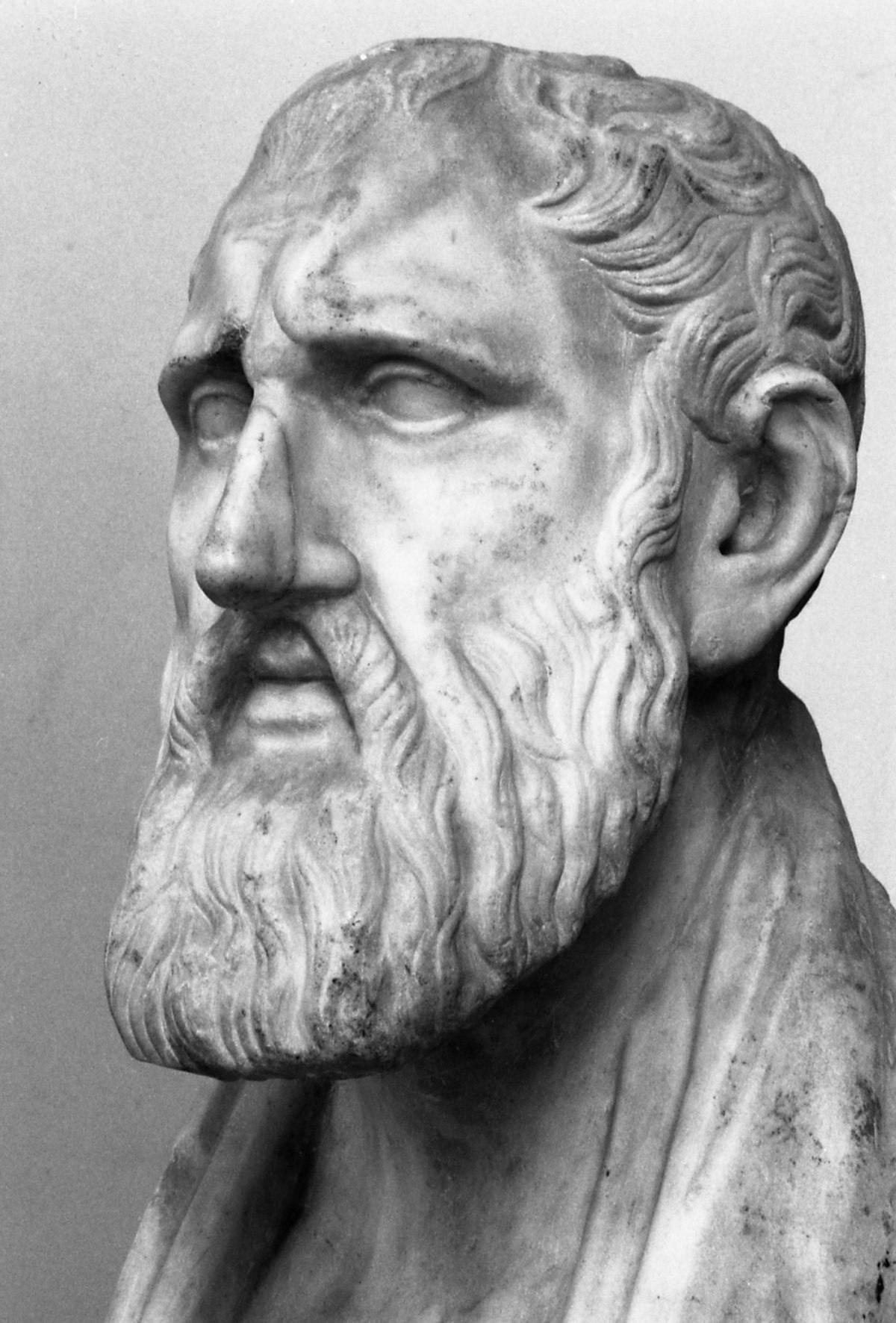 Black and white bust of Zeno of Citium, the founder of Stoicism, depicted with a beard and a serious expression. The sculpture shows a classical style, emphasizing his philosophical demeanor.