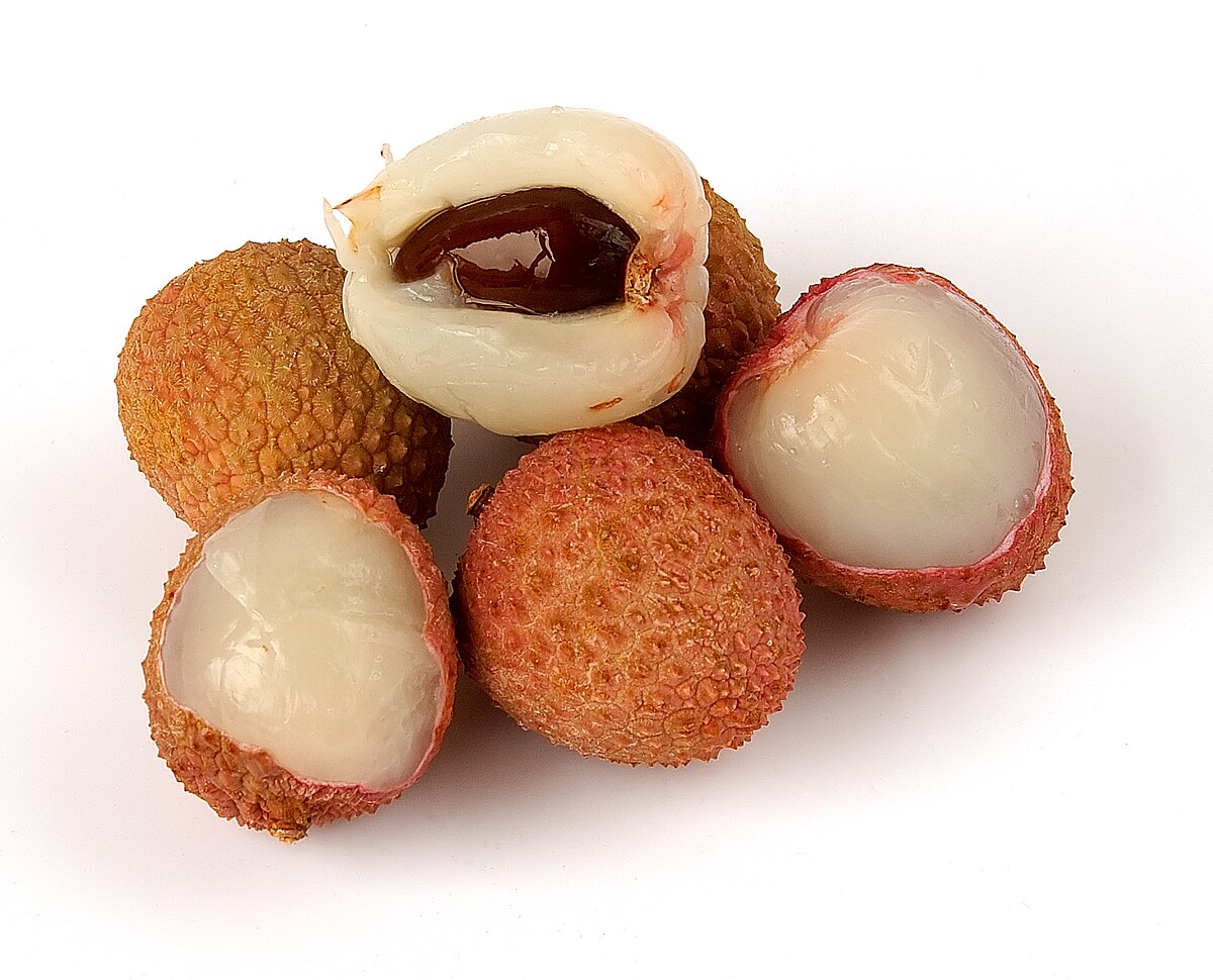 Close-up photograph of whole and peeled Litchi chinensis (lychee) fruits featuring rough reddish-brown rinds, translucent white flesh, and a dark brown seed. This fruit's distinct aroma is commonly associated with the Gewürztraminer grape variety.
