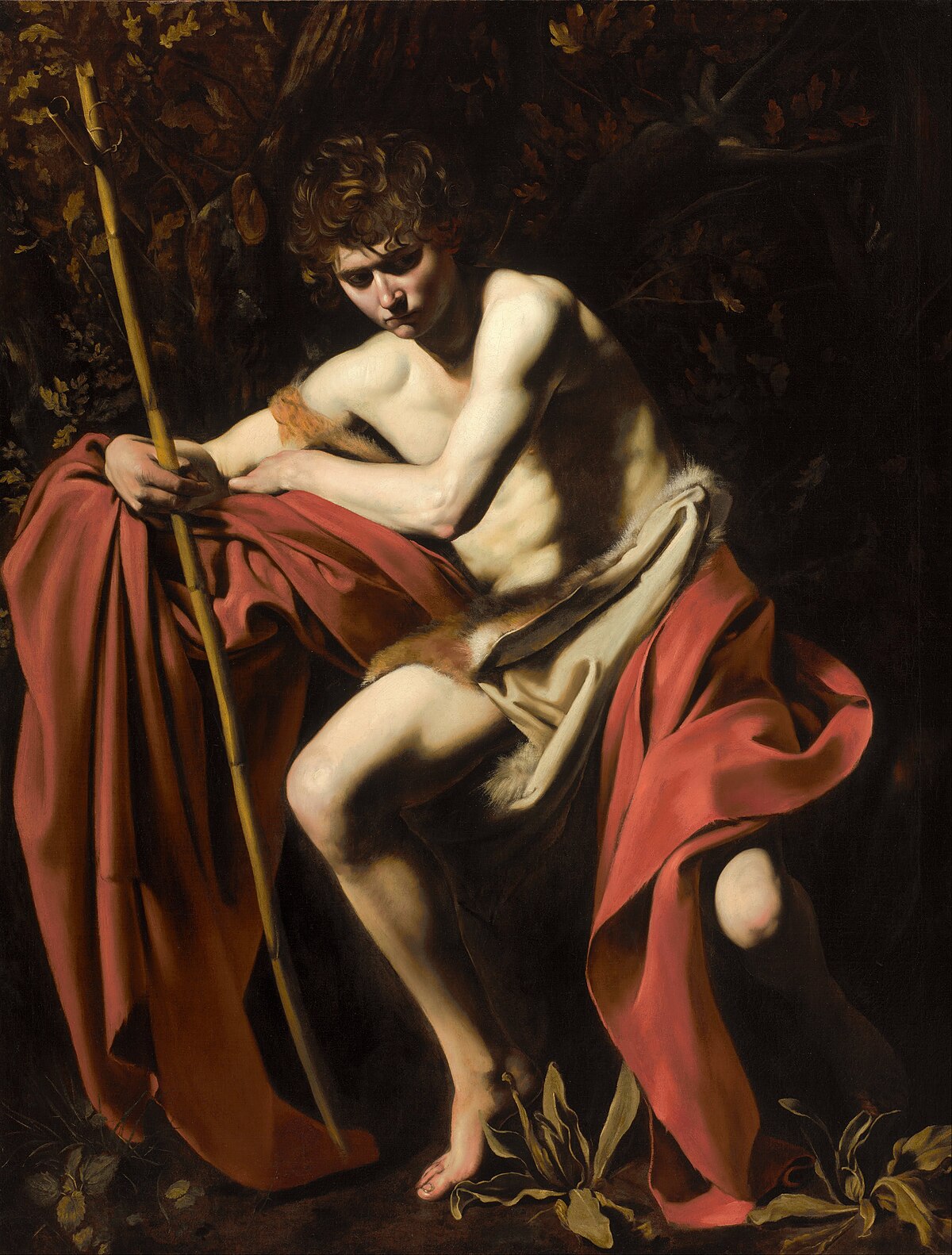 An oil painting by Caravaggio, titled "Saint John the Baptist in the Wilderness" (also known as "John in the Wilderness"), created in 1604 and located in the Nelson-Atkins Museum of Art. The painting uses tenebrism to illuminate John the Baptist, who is seated with a staff, against a dark, shadowy background.