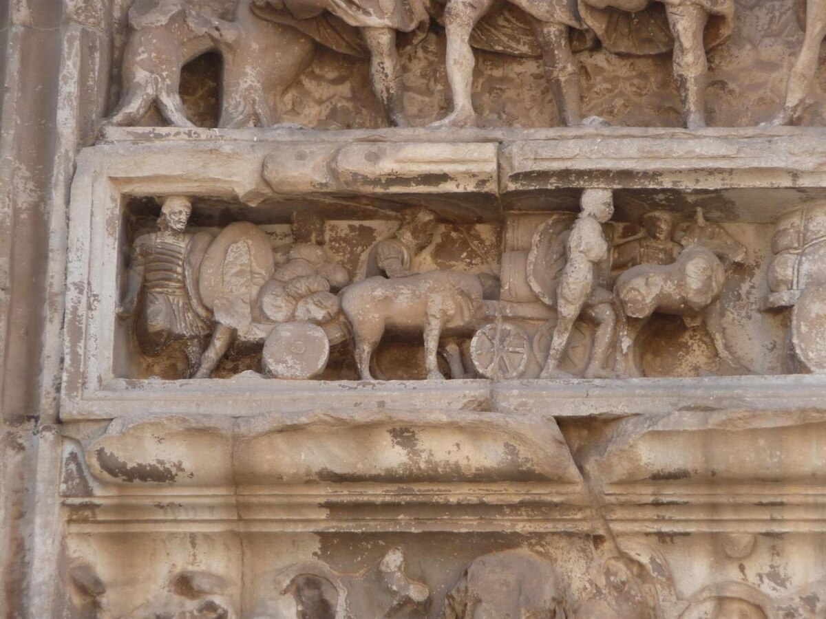 Detail from the Arch of Septimius Severus in the Roman Forum, depicting Roman soldiers in relief. The soldiers are shown wearing armor, possibly lorica segmentata, and carrying shields, alongside horses and carts.