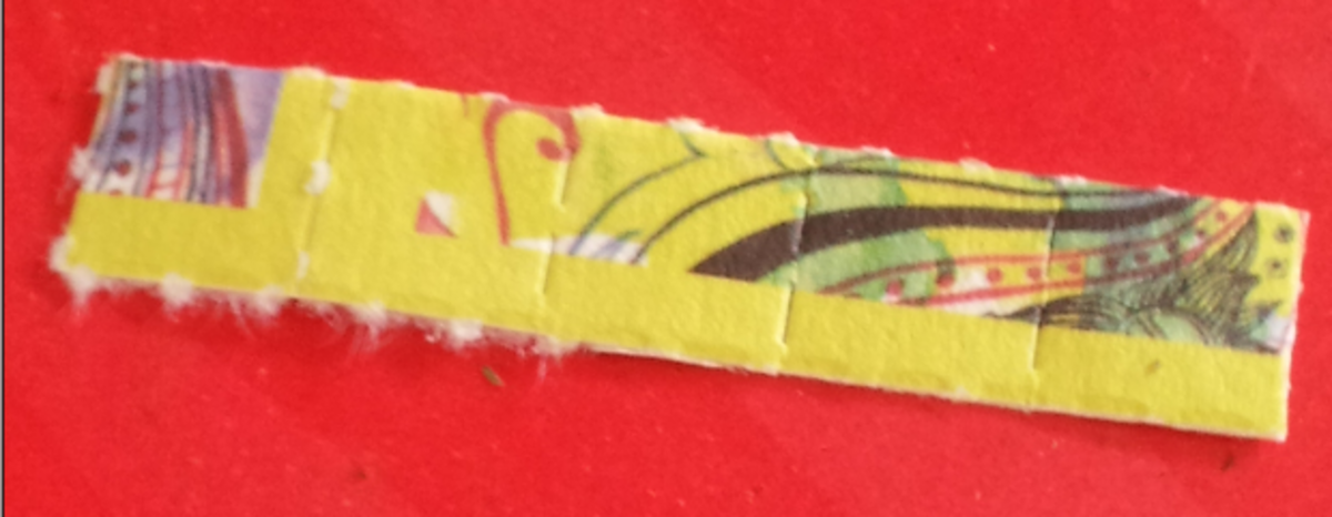 Close-up photograph of a "five strip" of LSD blotters, showing a perforated paper strip with colorful, abstract designs. The blotters are designed for sublingual or oral administration of LSD.