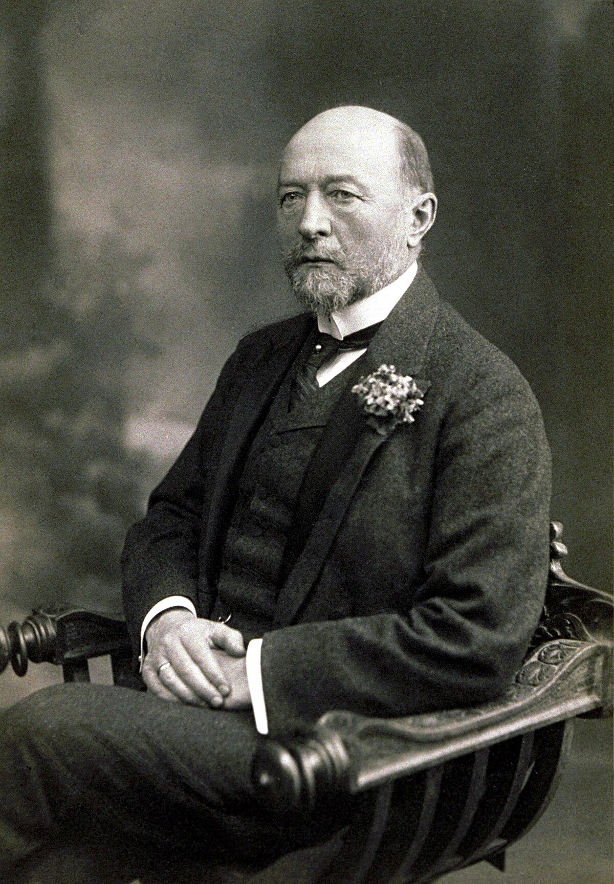 Portrait of Emil von Behring, who received the first Nobel Prize in Physiology or Medicine in 1901. He is seated, wearing a suit with a waistcoat and a flower pinned to his lapel, and has a beard and mustache.