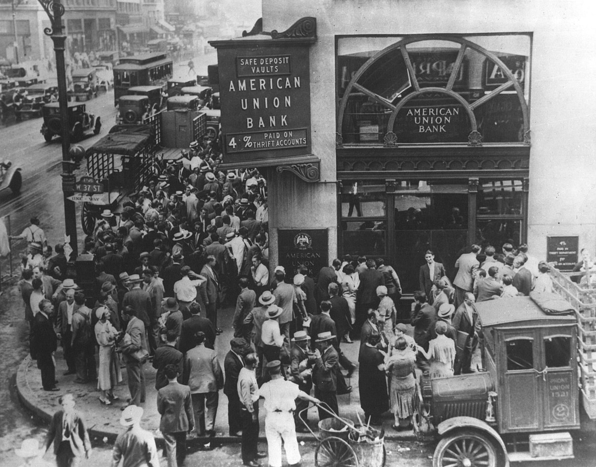 A black and white photograph of a large crowd gathered outside the American Union Bank in New York City on April 26, 1932, during a bank run. The bank's sign advertises "SAFE DEPOSIT VAULTS" and "4% PAID ON THRIFT ACCOUNTS."