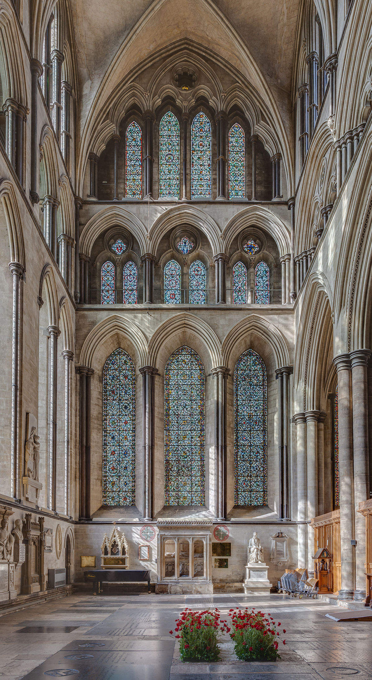 Interior view of Salisbury Cathedral, highlighting its nave with multiple levels of Gothic arches and stained glass windows. The lower level features large lancet windows, the middle level has smaller arched windows, and the upper level consists of a triforium gallery and clerestory windows, all contributing to the verticality of the space.