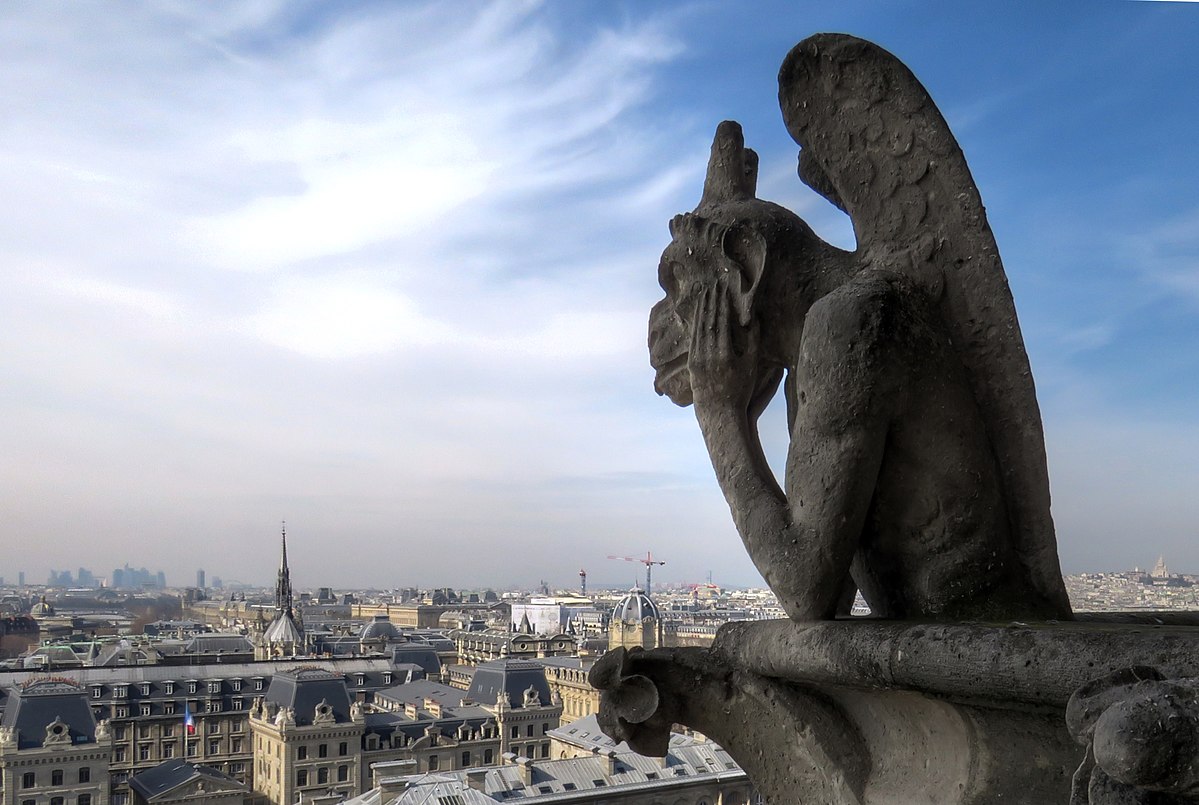 A gargoyle on Notre Dame Cathedral in Paris, overlooking the city skyline under a partly cloudy sky. The gargoyle, a grotesque figure, is positioned on the edge of the cathedral, with its hand resting on its chin.