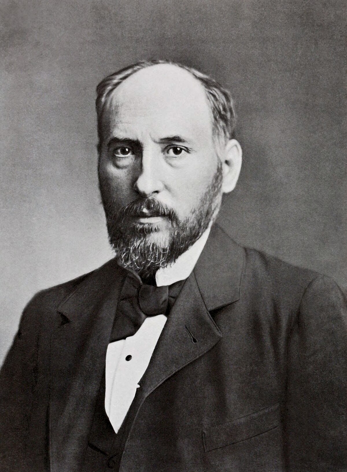 Portrait of Santiago Ramón y Cajal, a neuroanatomist from the 19th century, depicted with a beard and wearing a dark suit with a white shirt and bow tie.