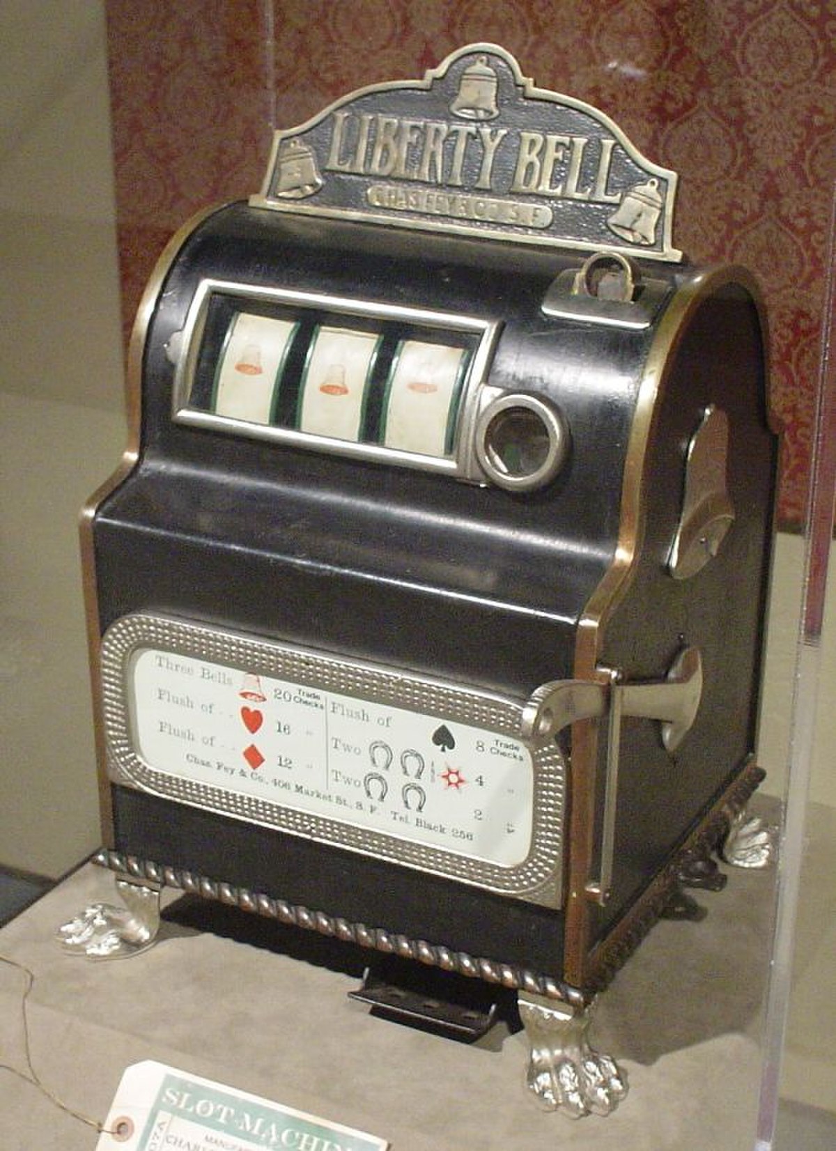 The 1899 "Liberty Bell" slot machine, manufactured by Charles Fey, featuring a black casing, three reels displaying bells, and a payout schedule on the front.