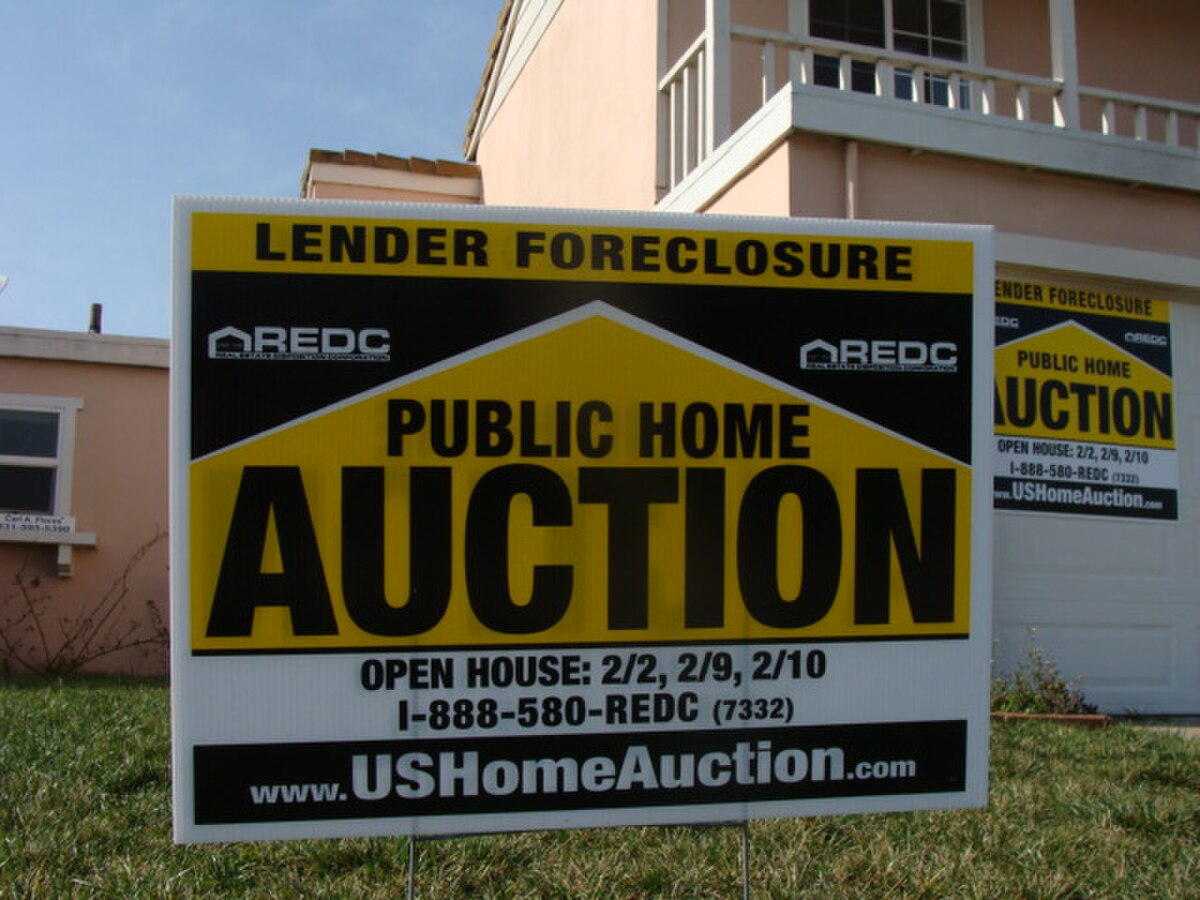 A "LENDER FORECLOSURE PUBLIC HOME AUCTION" sign is displayed on a lawn in front of a house in Salinas, California. The sign includes details about open house dates: "2/2, 2/9, 2/10" and a website "USHomeAuction.com."