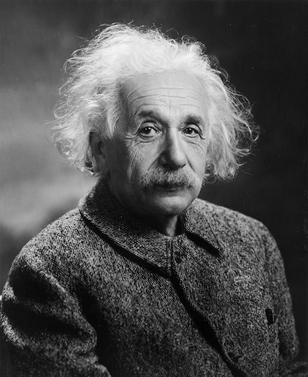 Portrait of Albert Einstein in 1947, showing him with his characteristic wild white hair and mustache. He is wearing a tweed jacket.