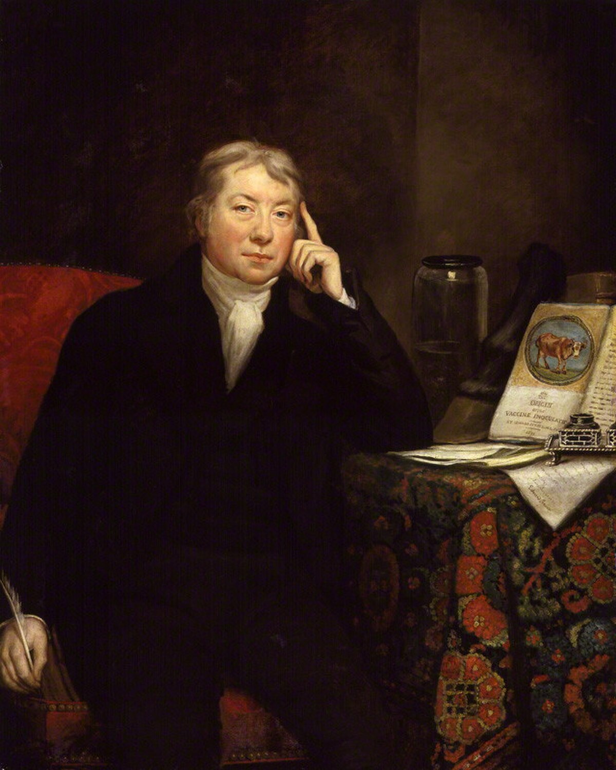 Portrait of Edward Jenner, painted by James Northcote. Jenner is seated, holding a quill pen, with his right hand resting on his chin, next to a book open to an illustration of cows and the title "An Inquiry into the Causes and Effects of the Variolae Vaccinae."