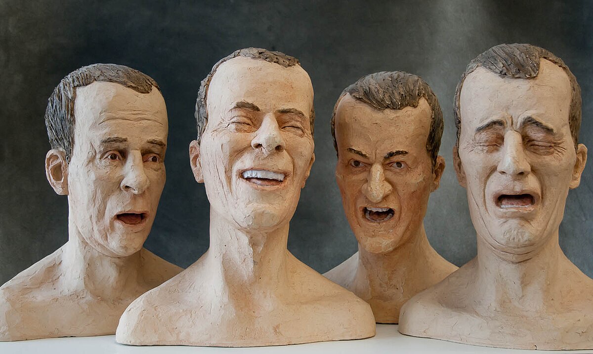 Four busts depicting different facial expressions of a man, ranging from surprise to joy, anger, and sadness. These sculptures illustrate how nonverbal cues communicate emotions.
