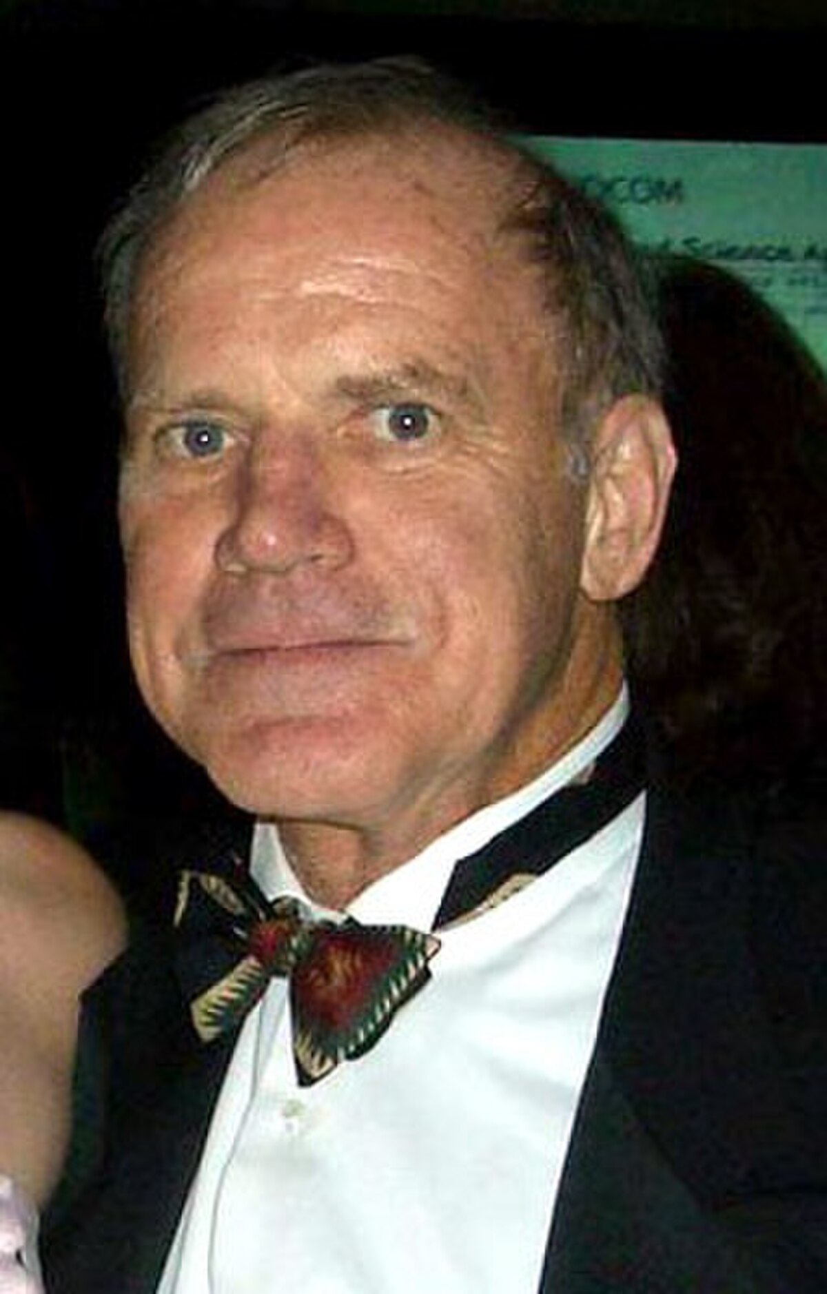 Portrait of Kary Mullis, a Nobel Prize-winning biochemist, wearing a tuxedo and a patterned bow tie. He is looking directly at the camera with a slight smile.
