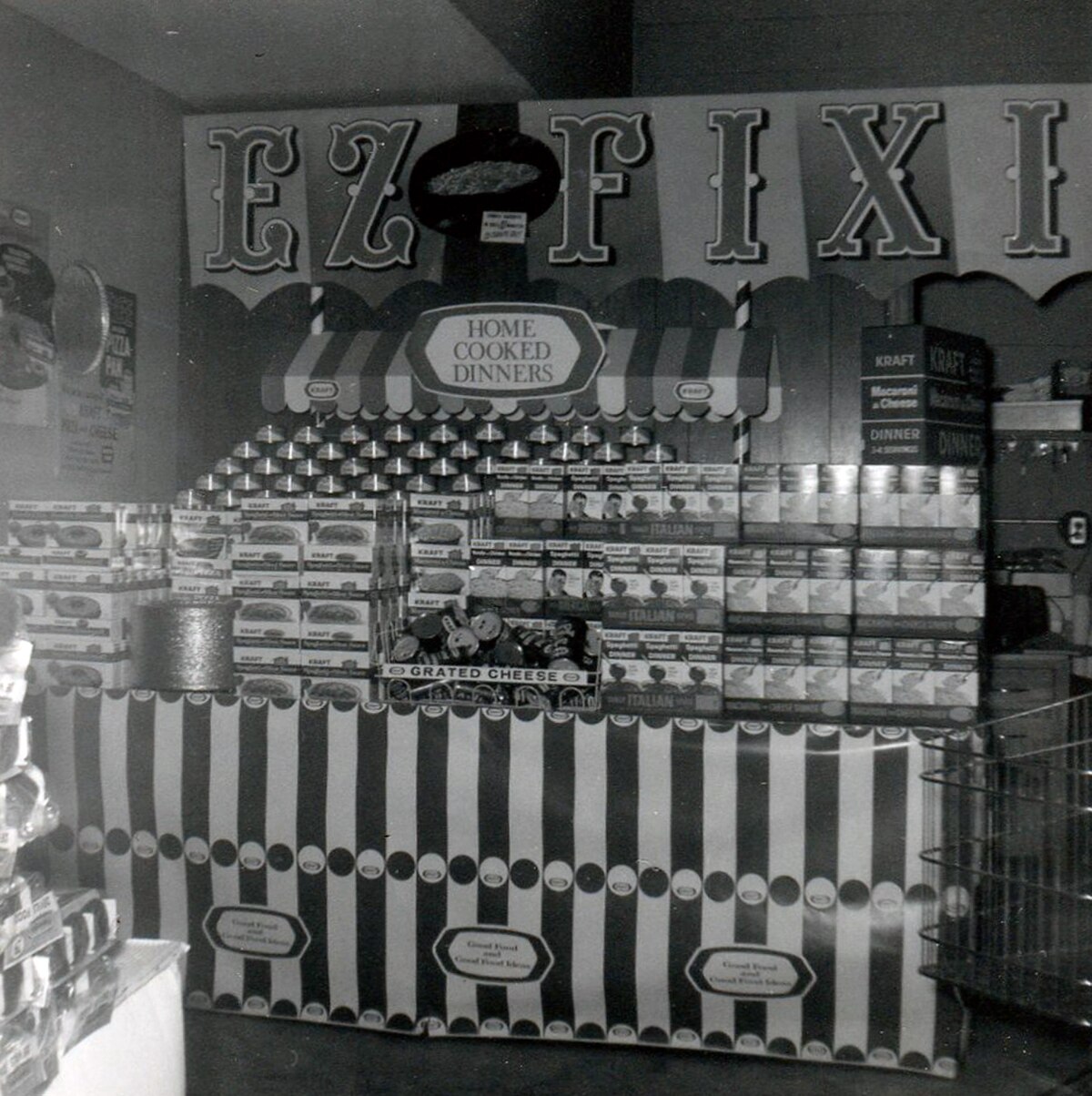 Grocery store display from 1966 featuring various "EZ FIXIN' HOME COOKED DINNERS" in cans and boxes. The display is decorated with a striped awning and a sign for "KRAFT" products.