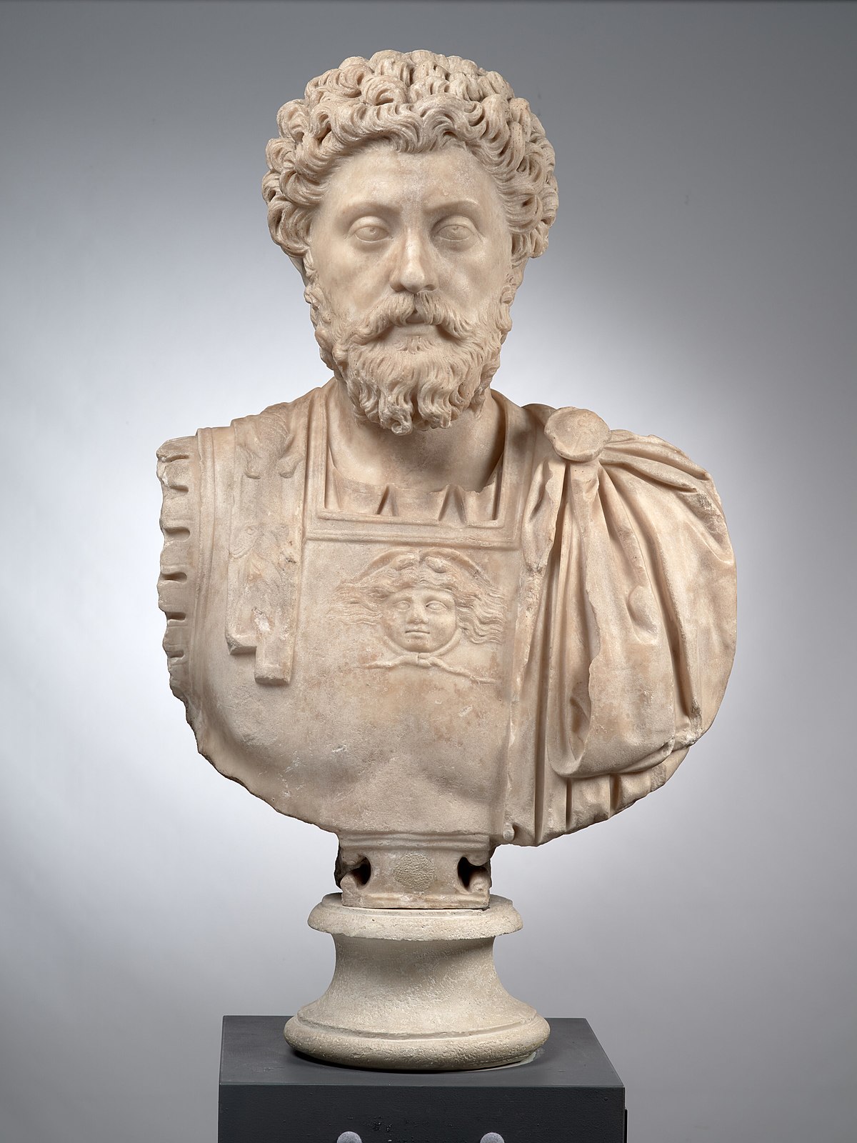 Marble bust of Marcus Aurelius, depicted with curly hair and a beard, wearing a cuirass with a gorgoneion on the chest and a paludamentum draped over his left shoulder.