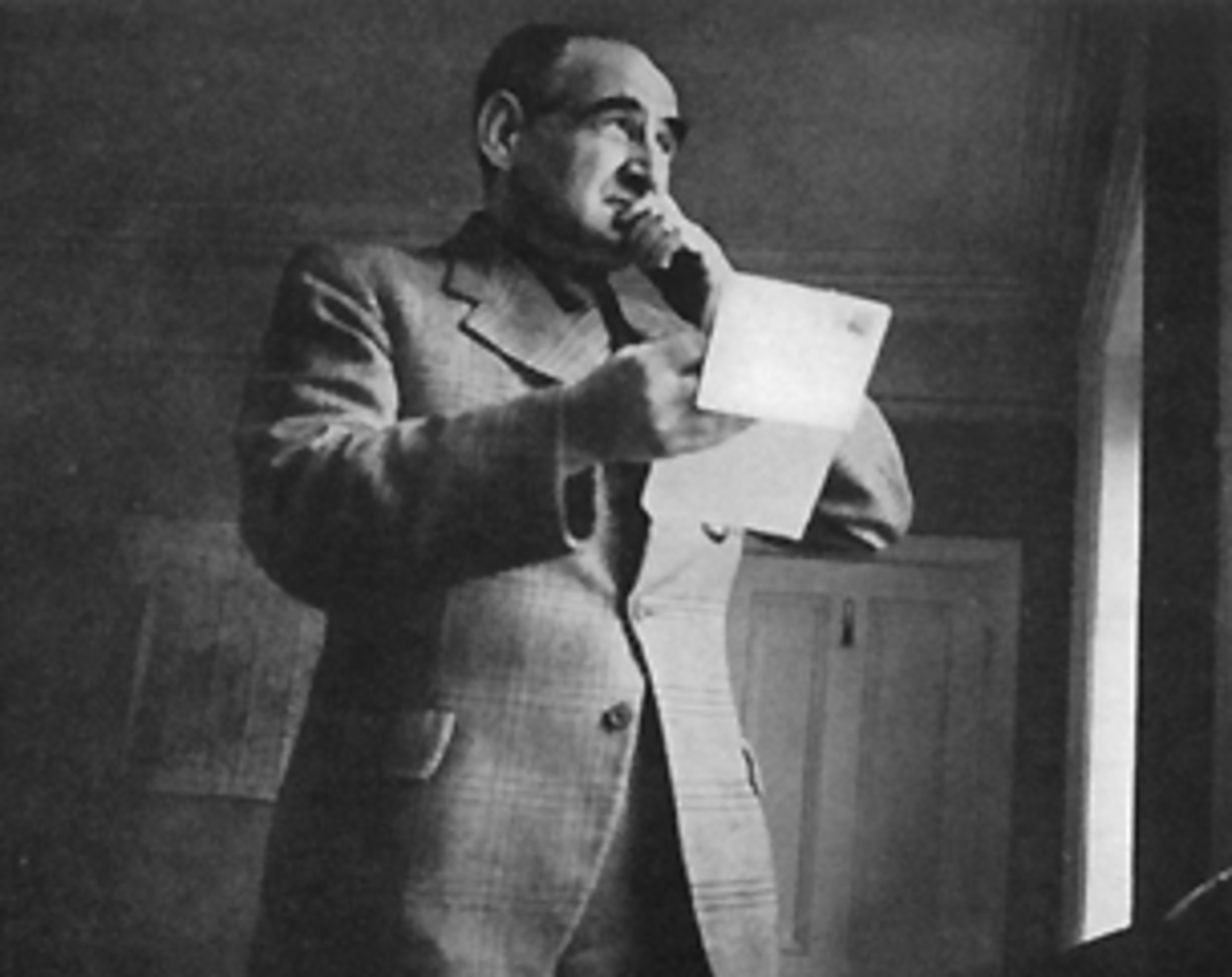 Black and white portrait of Frederick Marion, a mentalist, holding a piece of paper and speaking into a microphone. He is wearing a patterned suit jacket and looking upwards.