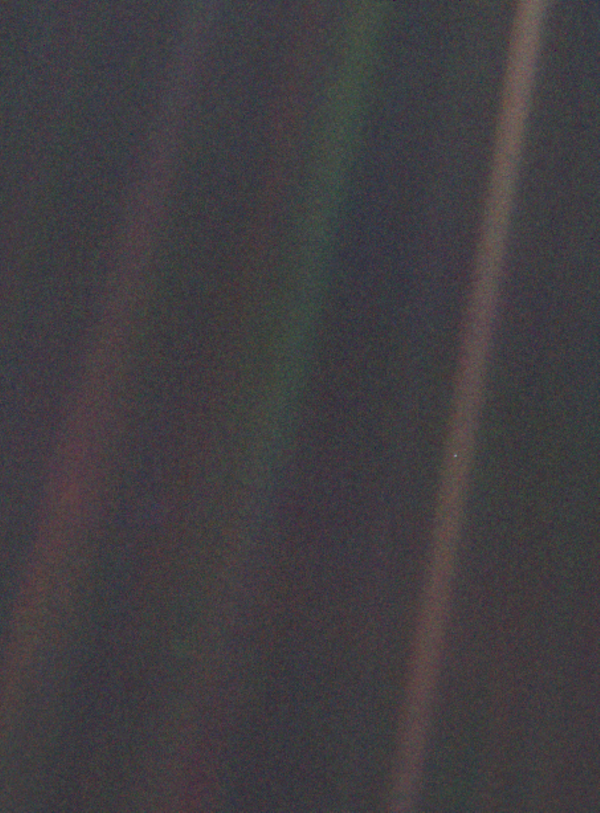 The iconic "Pale Blue Dot" image, showing Earth as a tiny, distant speck of light within a ray of sunlight, captured by Voyager 1. The image is dominated by the dark expanse of space and scattered light.